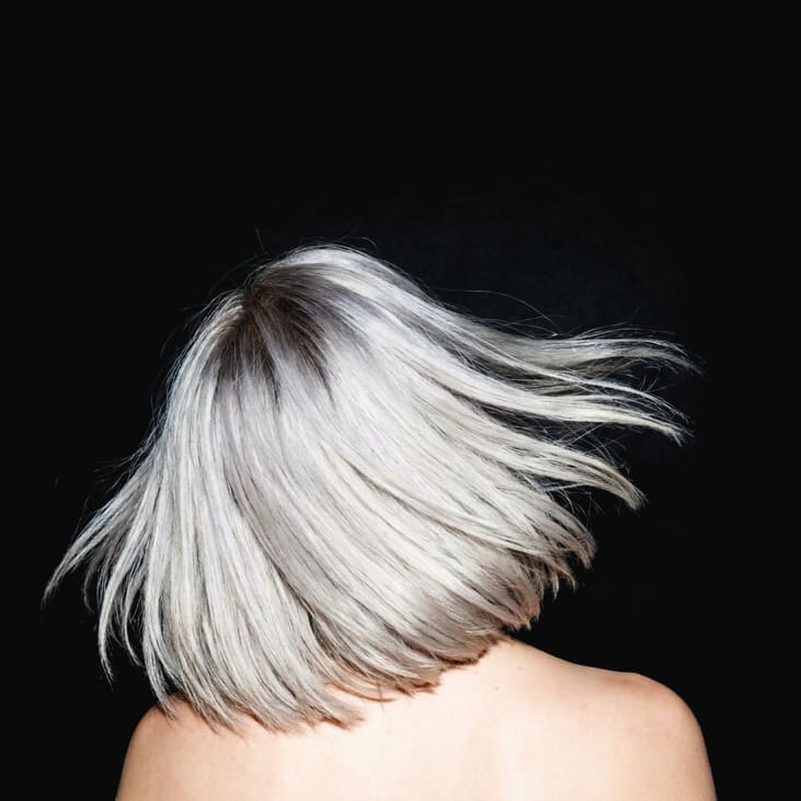 A silver blonde bob flipping mid air, seen from behind under hard flash