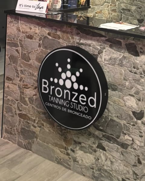 The round Bronzed lightbox on the front of the reception desk, against the stone wall