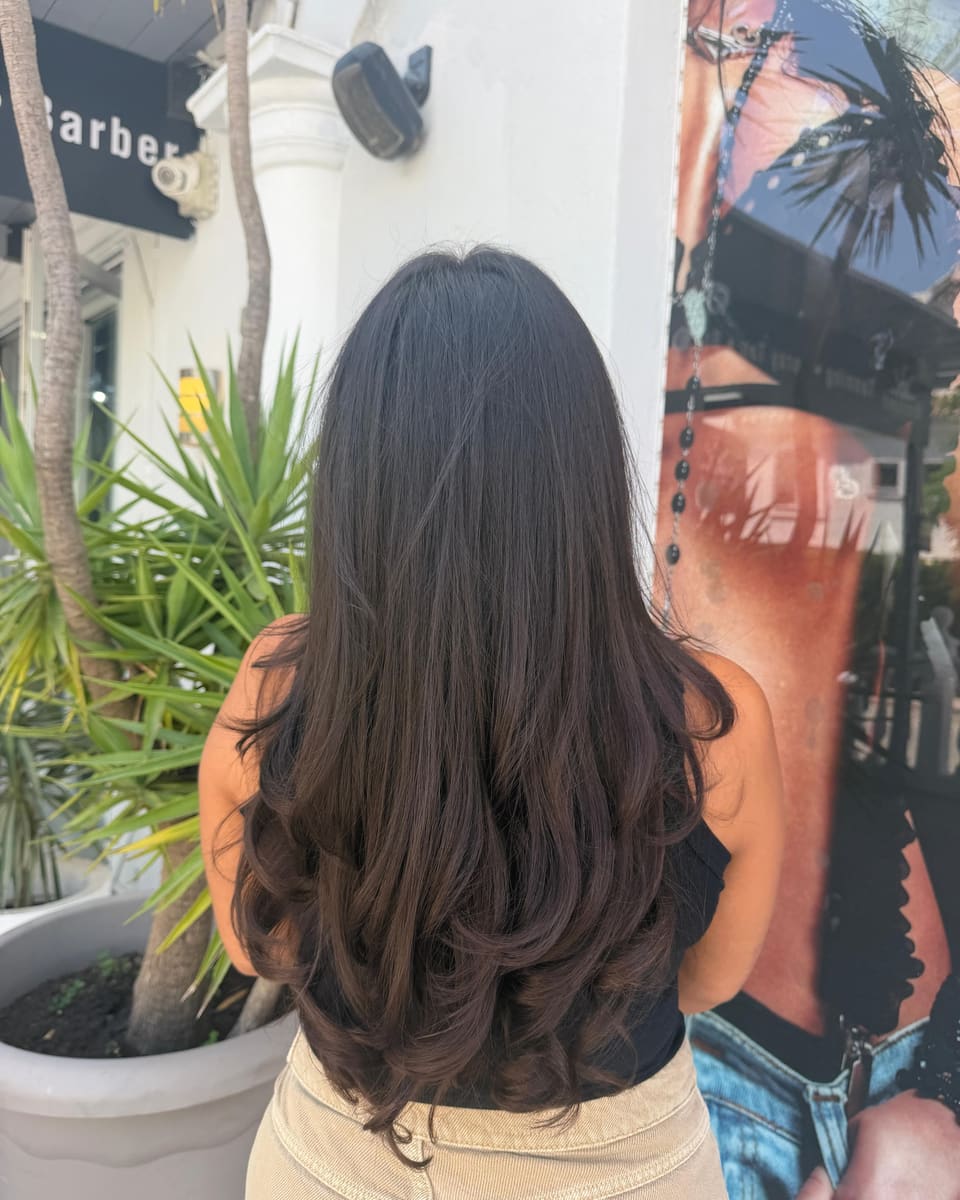 Long brunette waves from behind, outside the salon among the palms