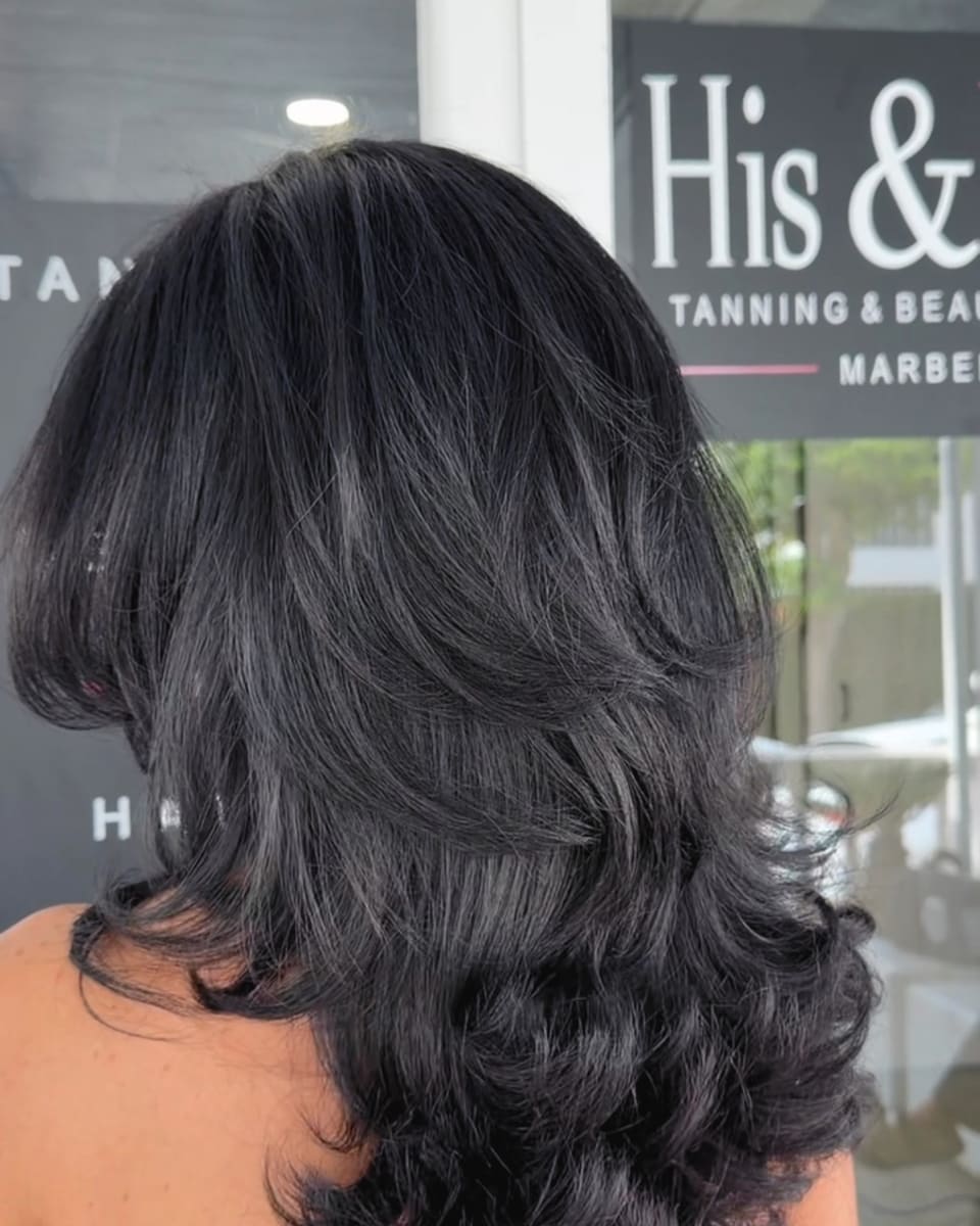 A glossy dark layered blow dry from behind, outside the His & Hers shopfront