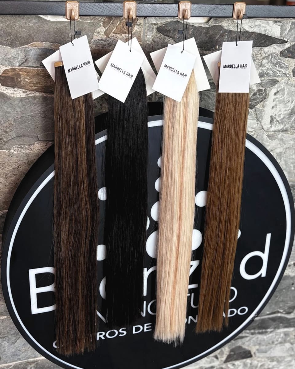 Hair extensions in four shades hanging on the Bronzed sign, on the stone wall